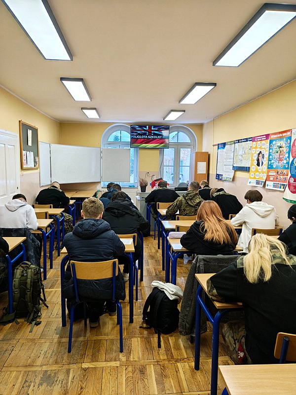 Uczniowie rozwiązują zadania konkursowe w ławkach szkolnych